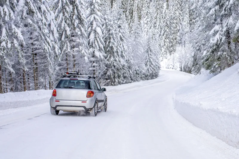 car-on-the-road-in-the-mountains-surrounded-bt-fir-trees-covered-by-snow