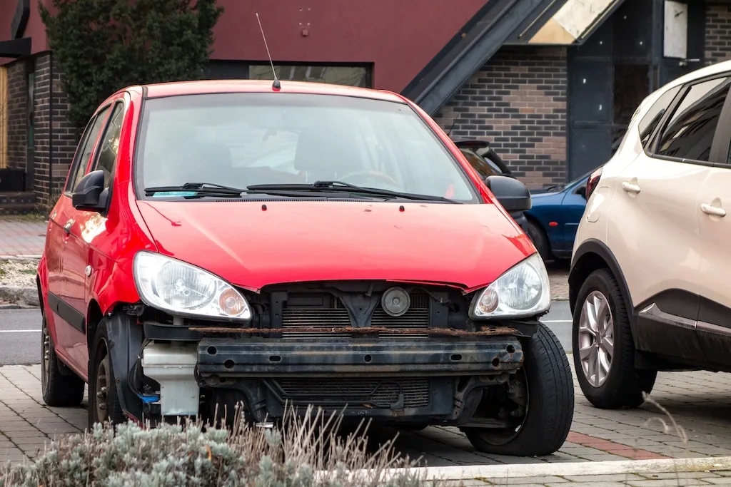 a-small-red-hatchback-car-with-missing-frontal-par-after-a-traffic-accident-with-radiator-visible